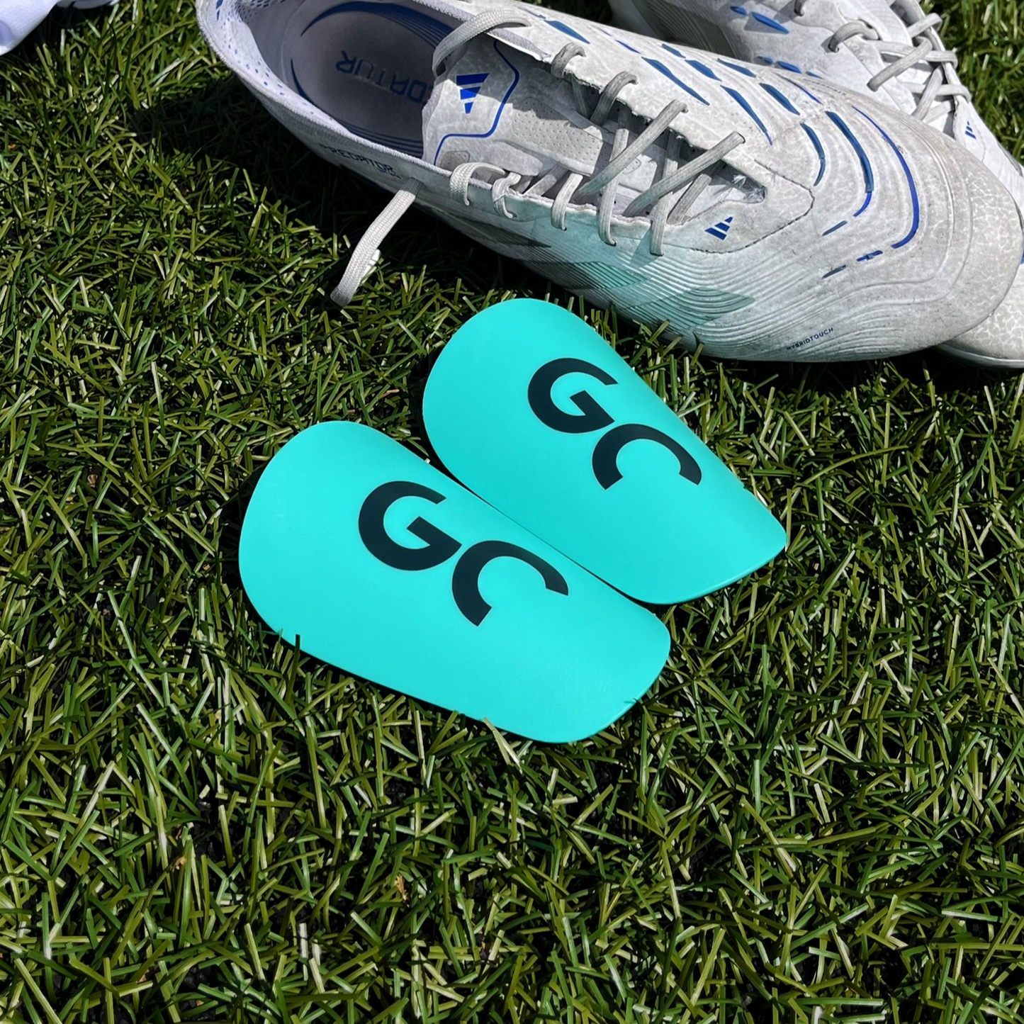 Mini protège-tibias discrets pour footballeurs confort et compacts, posées sur terrain de football| Game Changer
